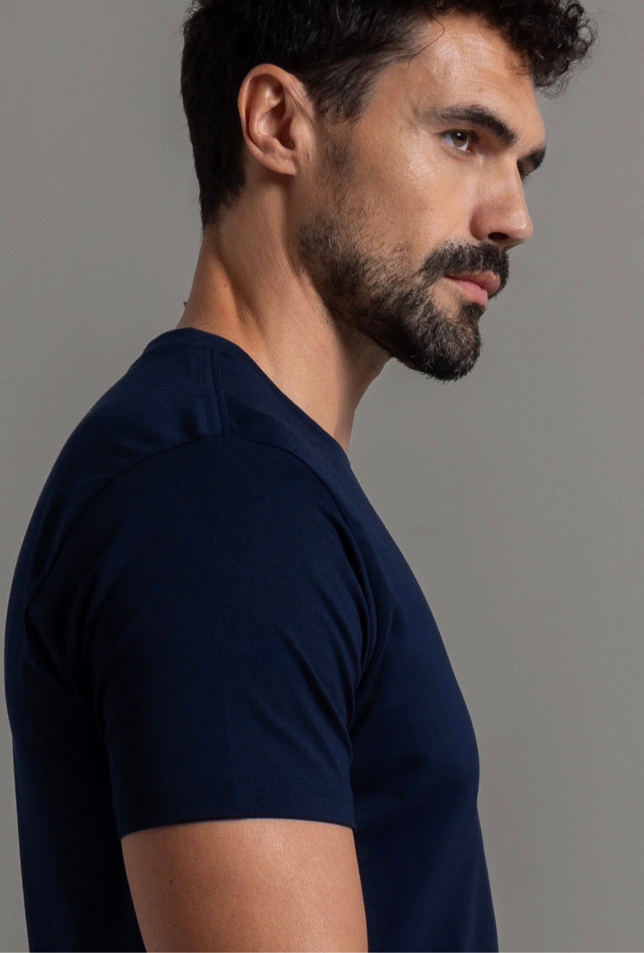This image features a close-up profile view of a man wearing a midnight blue cotton blend shirt. The shirt boasts a sleek and snug fit, accentuating the model's torso.