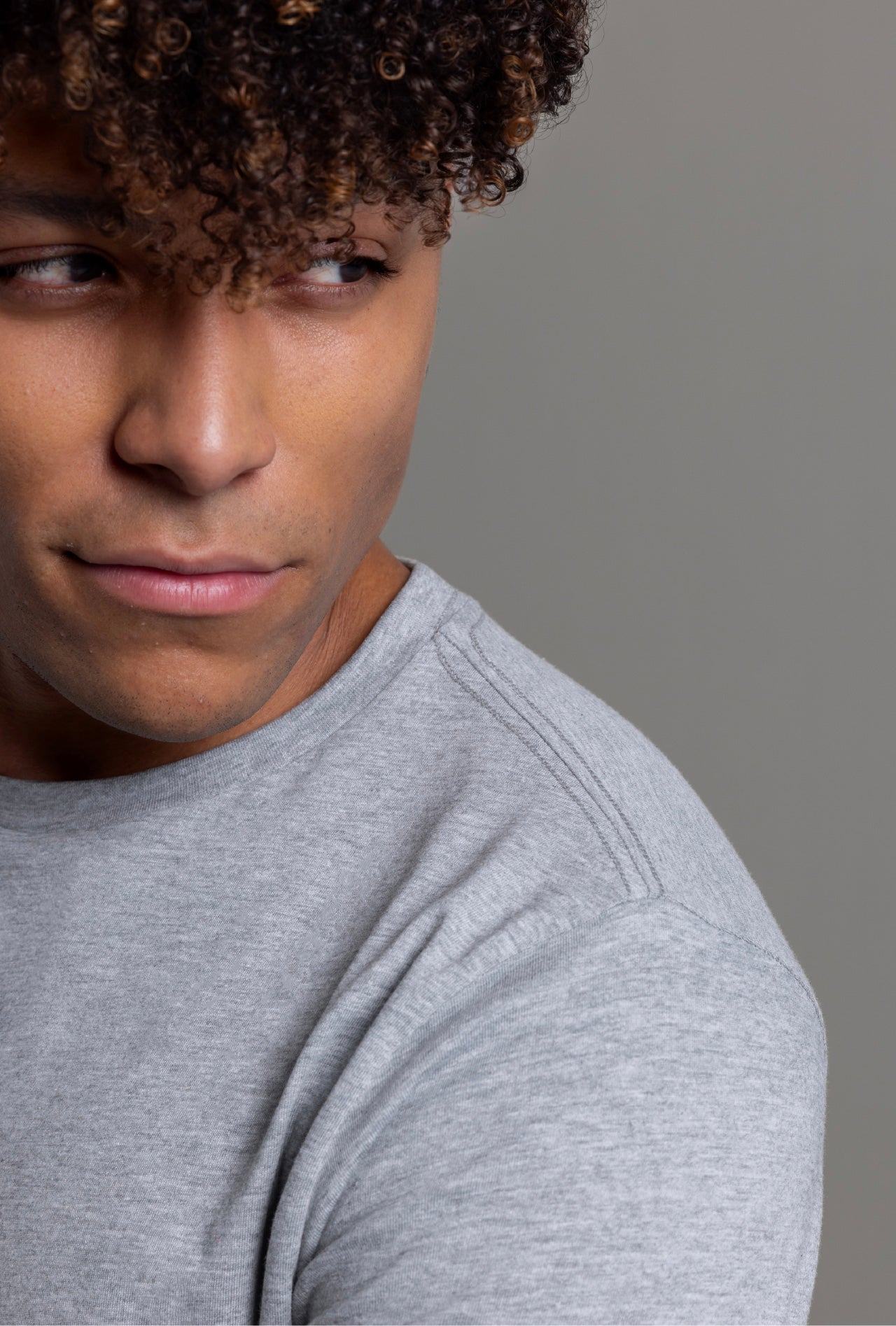 A close-up of a person wearing a heather grey cotton blend t-shirt.
